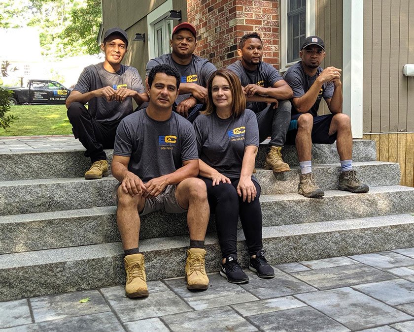 Owner posing with the team on stone paved stairs steps.